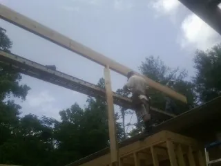 Carpenter setting a ridge beam over a new addition frame — Ice Dam Removal by Roofing Brothers in Birch River