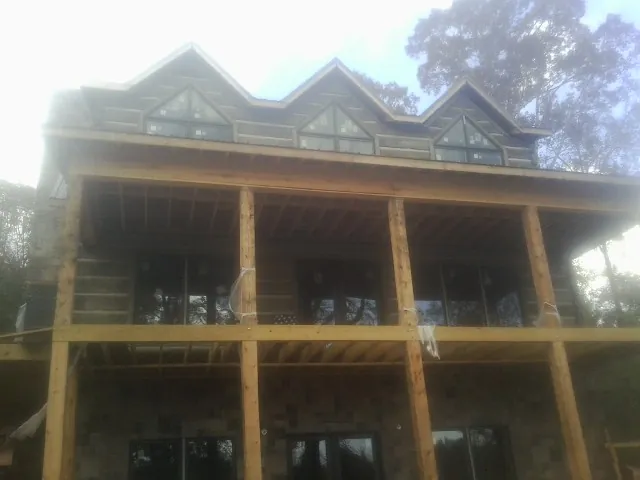 Dormers and porch framing on a large log home under construction — Roof Coating work by our crew in Birch River