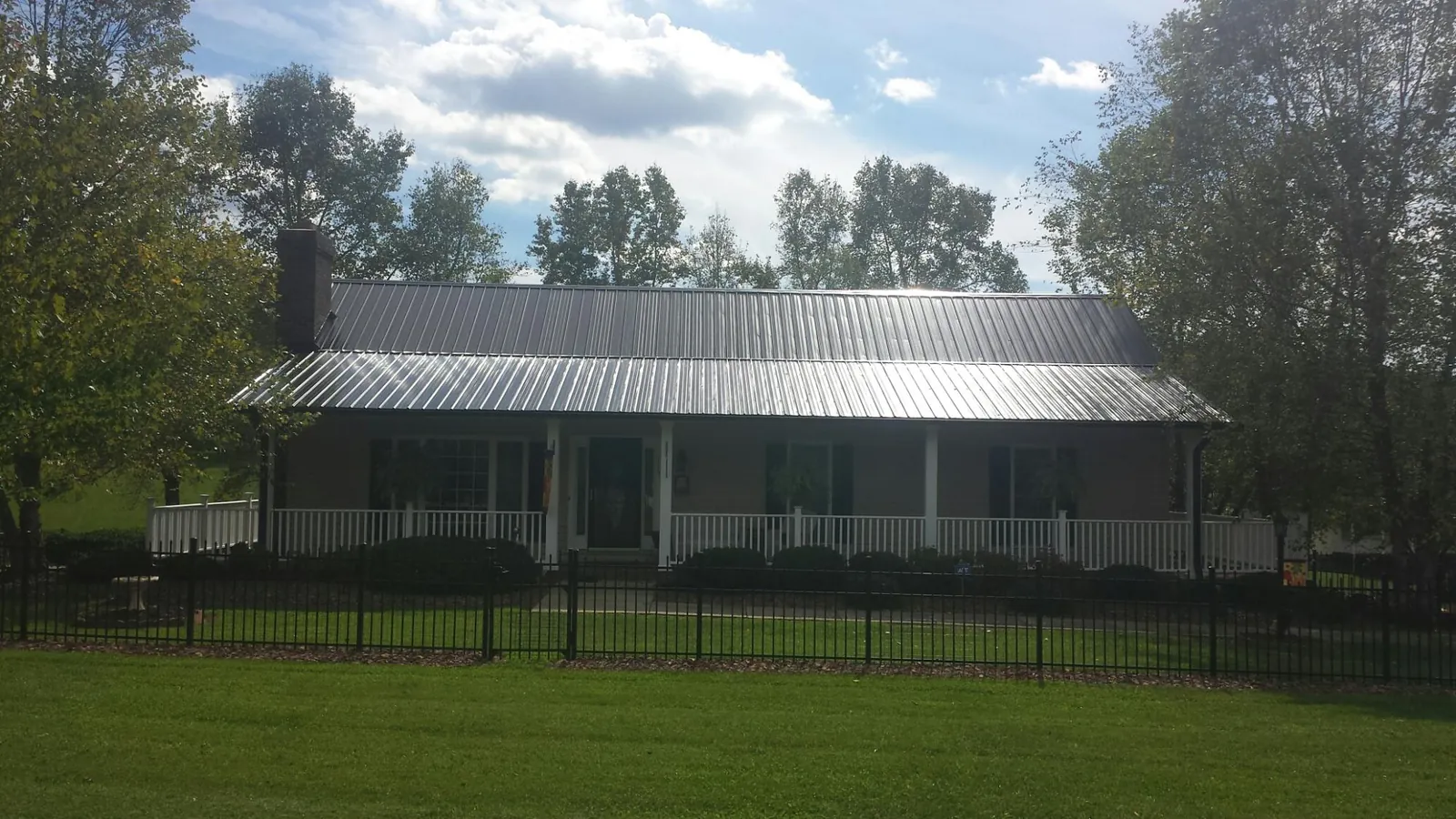 Gray metal roof on a brick ranch with a full width front porch — Gutter Guard Installation work by our crew in Birch River