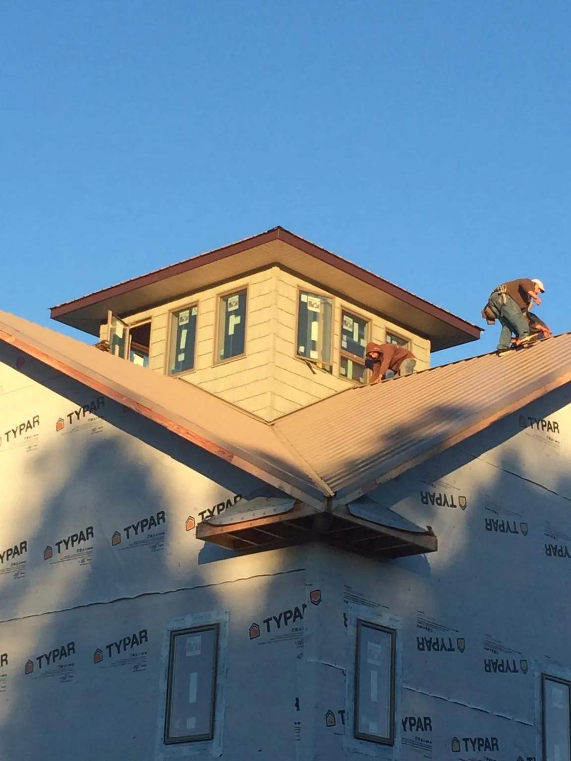 Roofers working around a rooftop cupola on a new metal roof at sunset — Roof Waterproofing in Birch River by Roofing Brothers